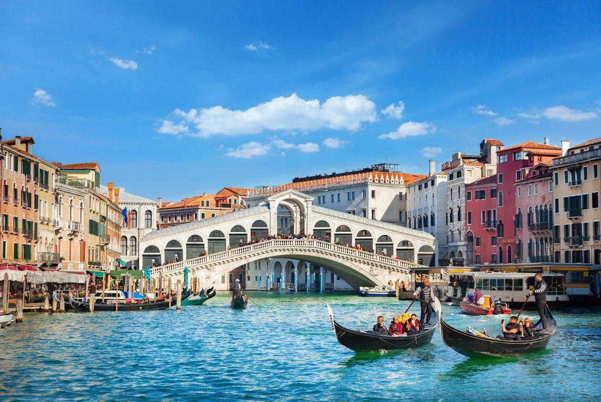 Vista del Puente de Rialto en Venecia, Italia, con gente caminando sobre él.
