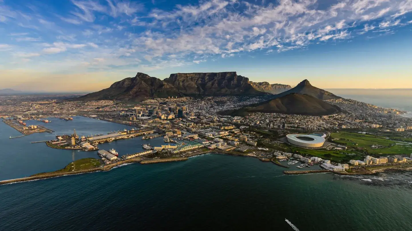 Vista aérea de Ciudad del Cabo, Sudáfrica, con la Montaña de la Mesa en el fondo, el océano en primer plano y el estadio Cape Town en el lado derecho.