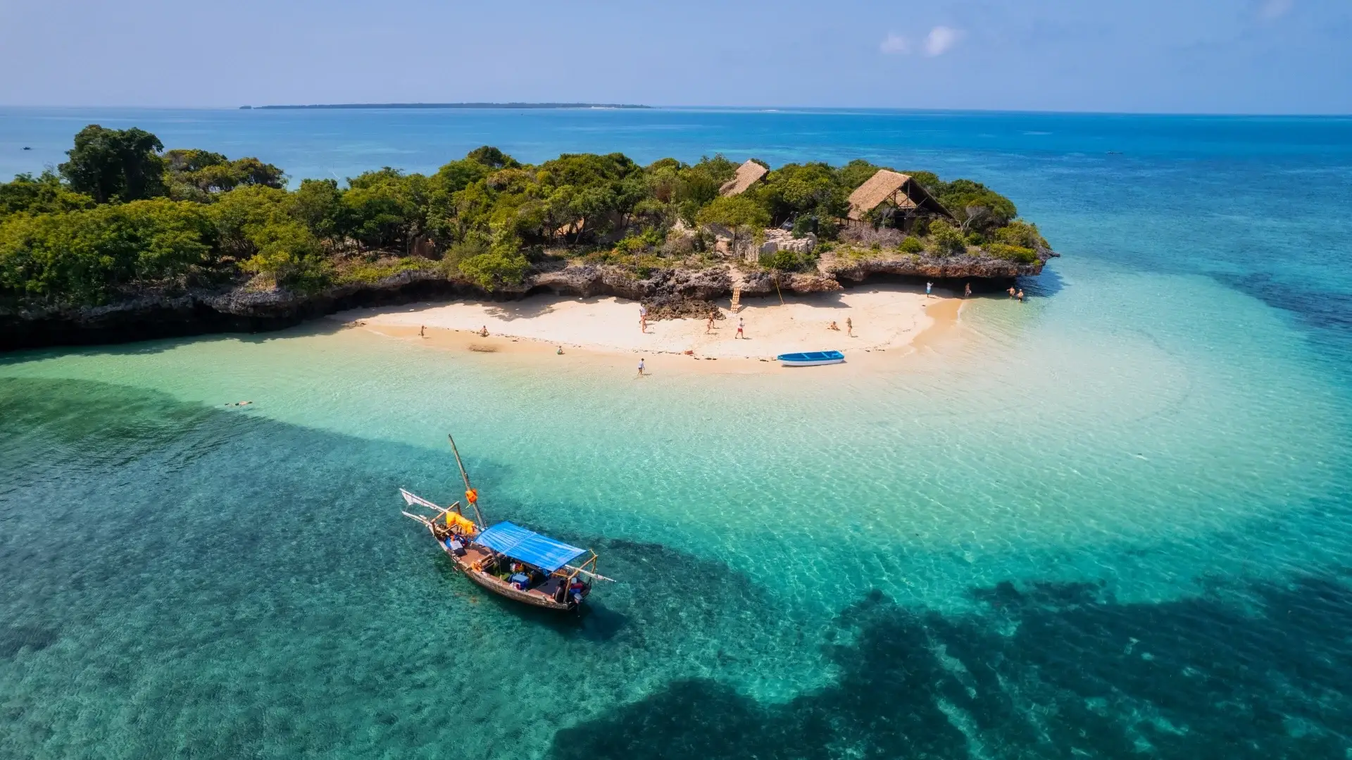 Vista aérea de la costa de Zanzíbar, Tanzania, con aguas turquesas, arena blanca y vegetación exuberante.