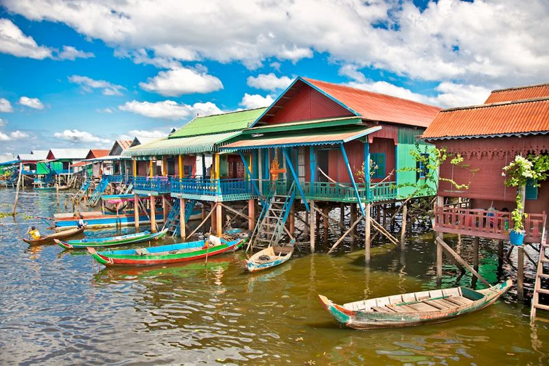 Pueblo flotante en el lago Tonlé Sap, Camboya, con casas sobre pilotes y barcas navegando.