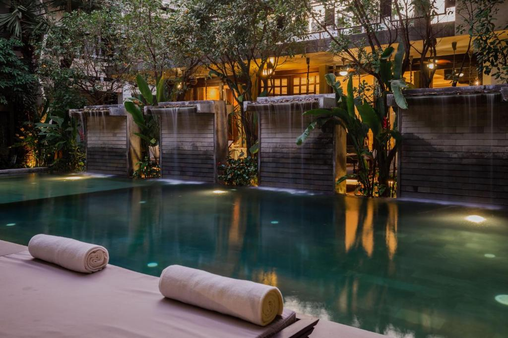 Piscina del hotel Jaya House River Park en Siem Reap, con tumbonas.