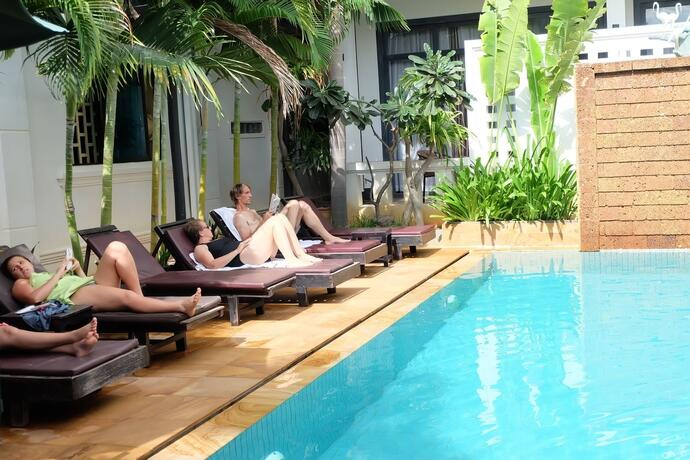Personas tomando el sol en tumbonas junto a la piscina del hotel Tanei Boutique Villa en Siem Reap.